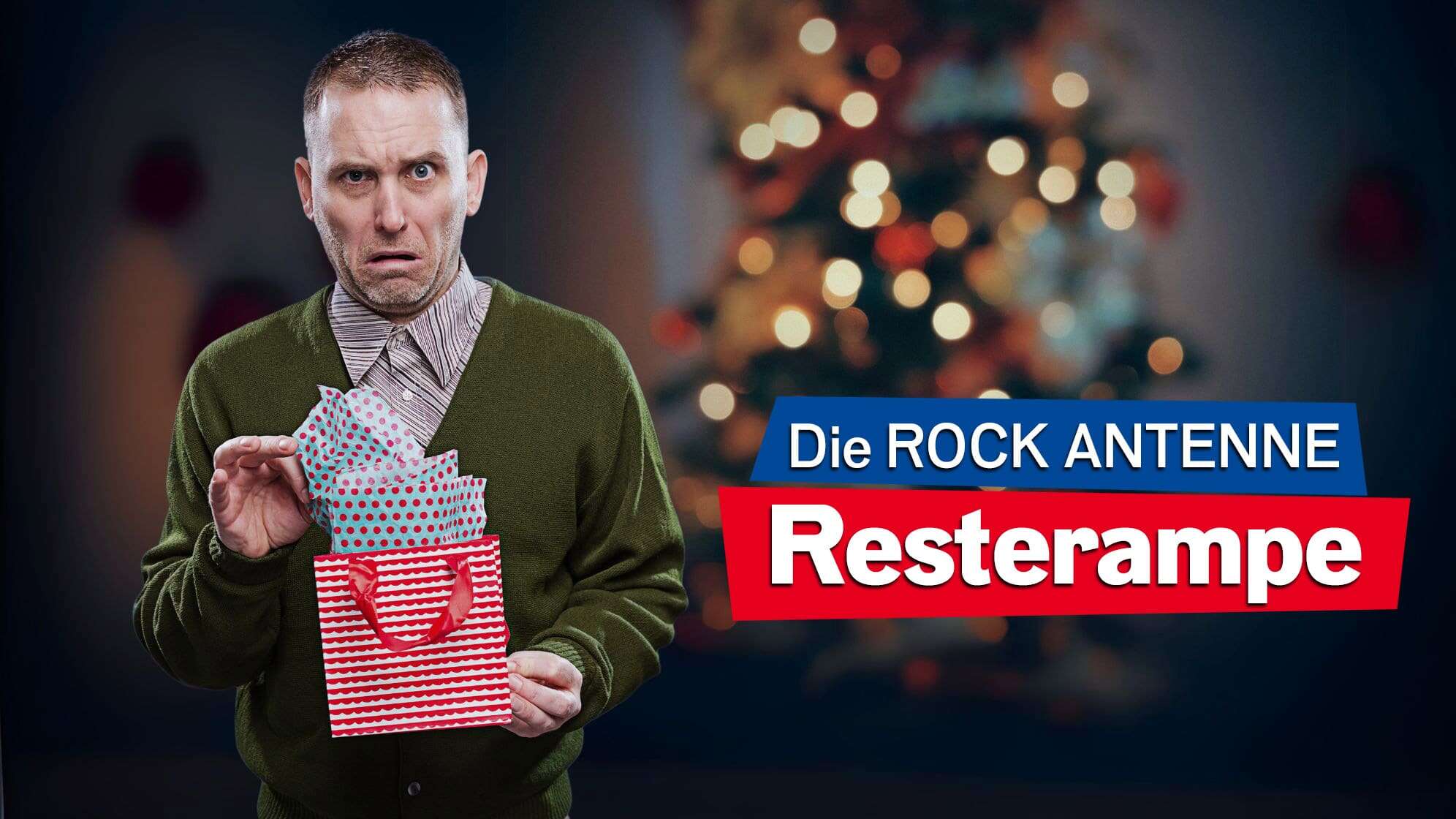 Ein Mann steht mit einem Weihnachtsgeschenk vor einem Weihnachtsbaum im Hintergrund und sieht überrascht und unzufrieden aus; Dazu der Text: Die ROCK ANTENNE Resterampe