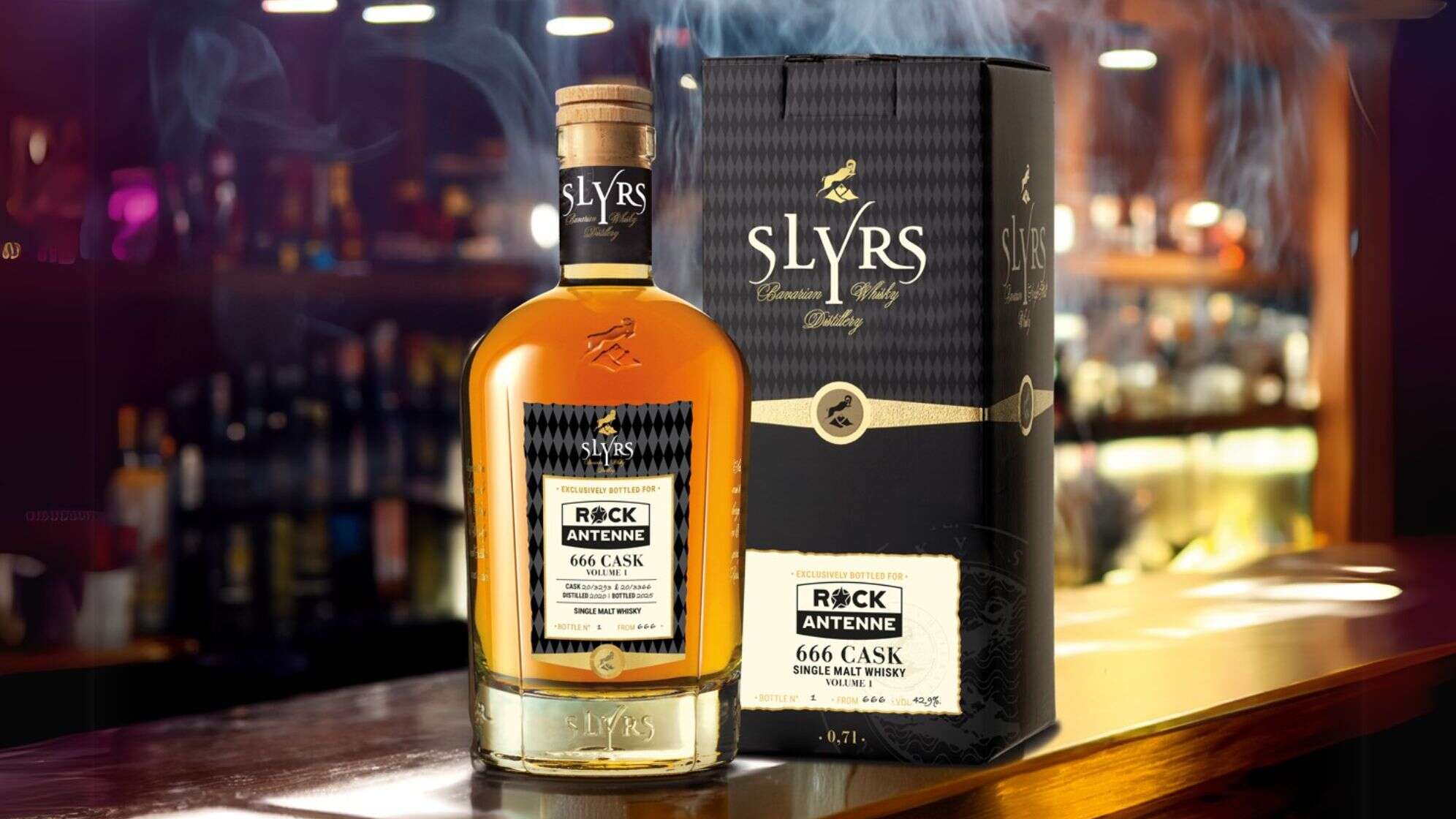 Eine Flasche des limitierten ROCK ANTENNE Whiskys von Slyrs - 666 Cask Vol. 1 Edition 2025, eine Flasche samt Geschenkkarton steht auf einem Bartresen