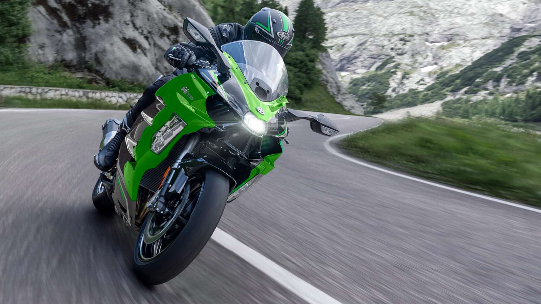 Eine Kawasaki Ninja H2 SX SE fährt auf einer Straße, im Hintergrund Berge