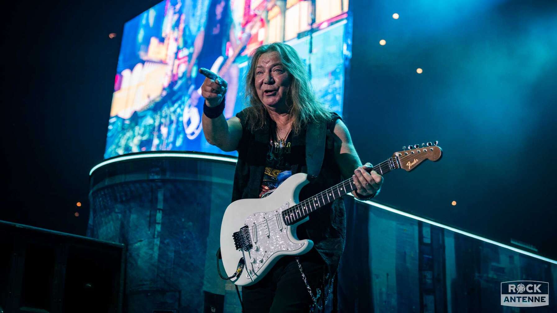 Dave Murray beim Konzert, er zeigt auf die Zuschauer