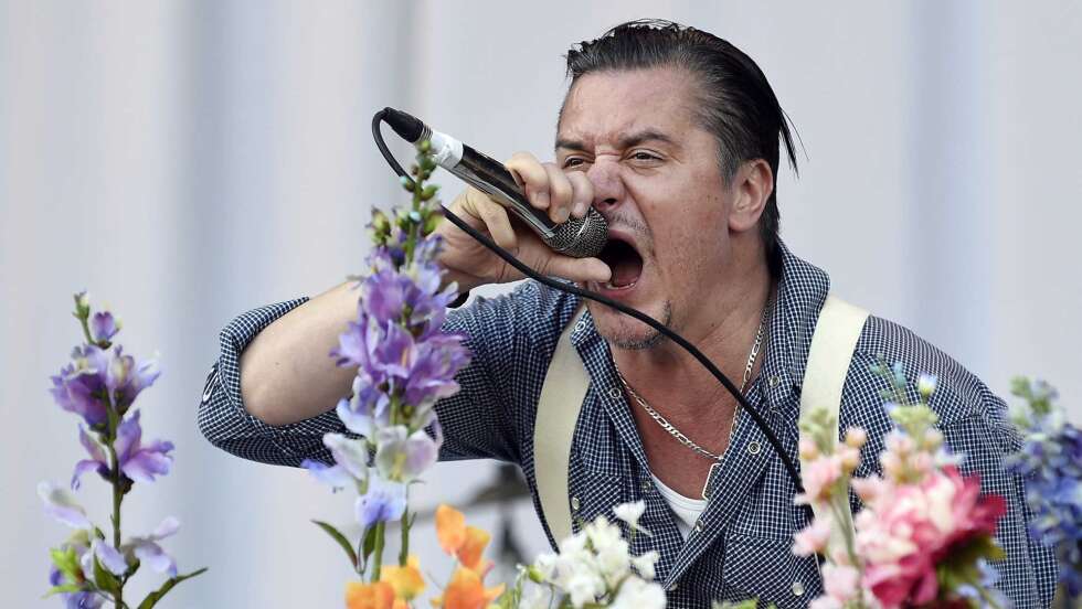 Mike Patton hinter Blumen mit einem Mikrofon, in das er singt