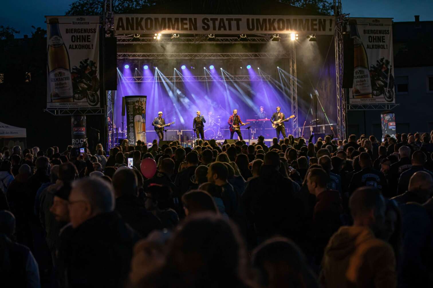 Die ROCK ANTENNE Band tritt bei der Motorradsternfahrt Kulmbach auf. Blick von hinten aus dem Publikum auf die Bühne.